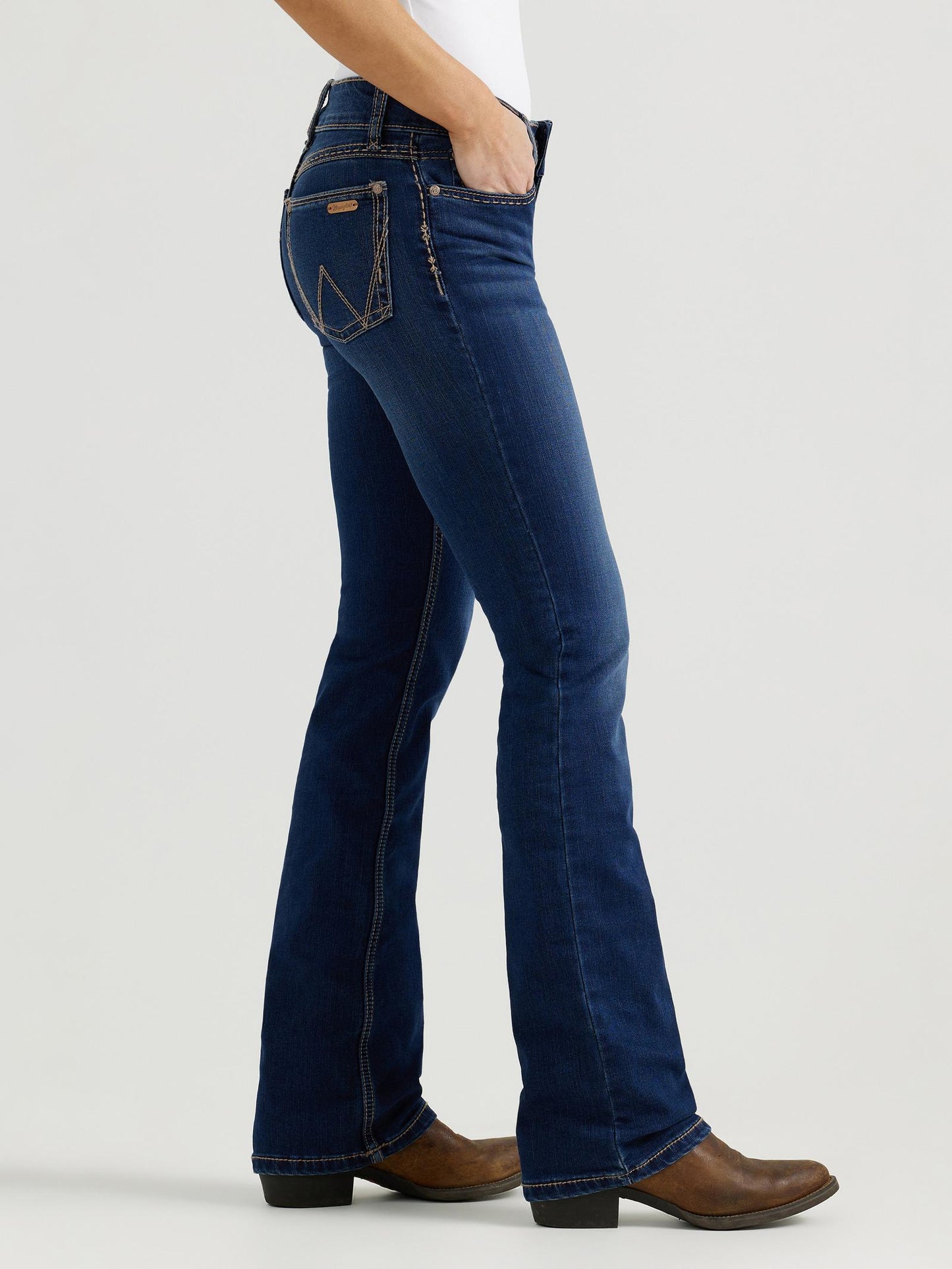 Person wearing blue jeans and brown boots on a white background
